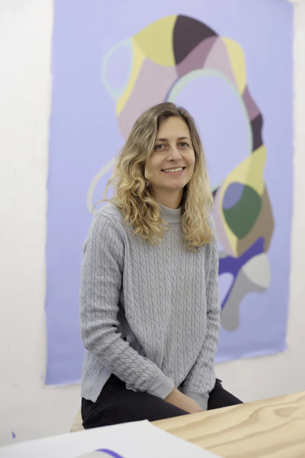 Florencia Trucco in a gray sweater standing in front of abstract art